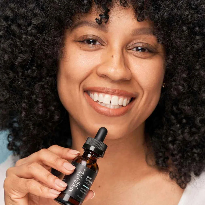 Woman holding a bottle of a skincare product with a dropper.