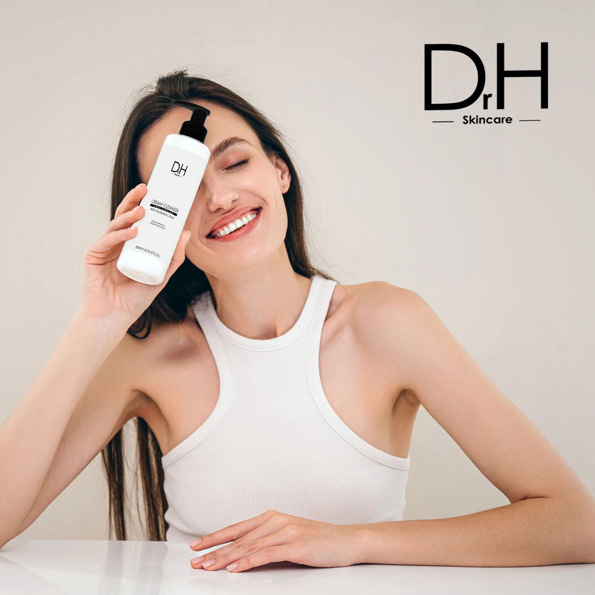 Woman holding a Dr H skincare product with a plain background