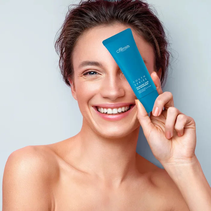 Woman holding a blue bottle of Cetaphil cleanser against a light gray background