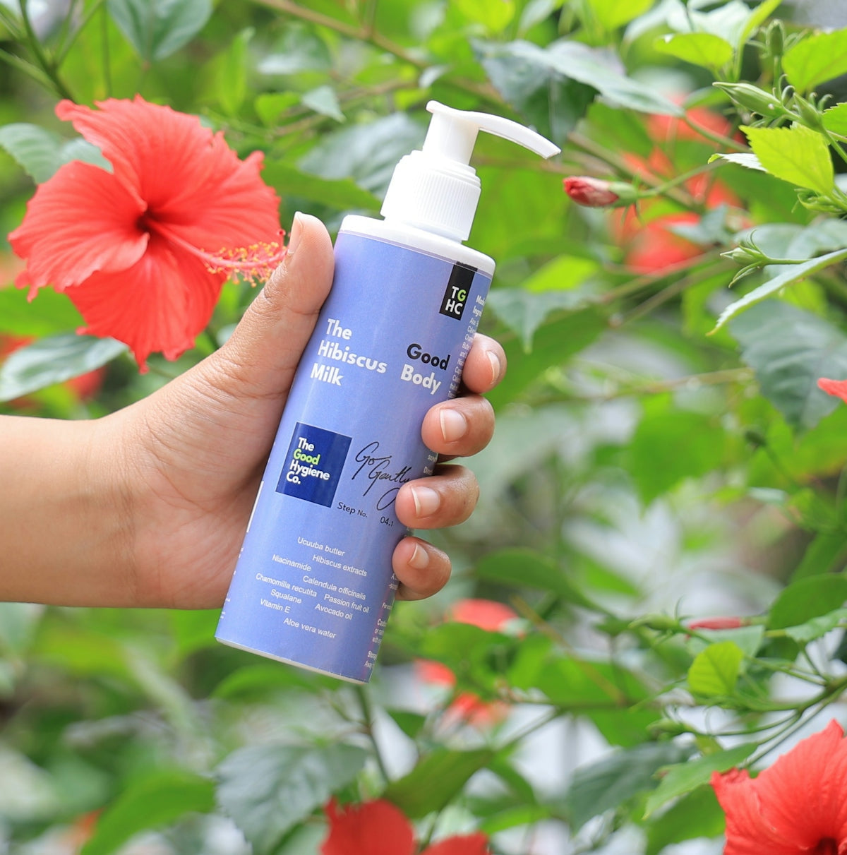 Hand holding a bottle of hibiscus body lotion.