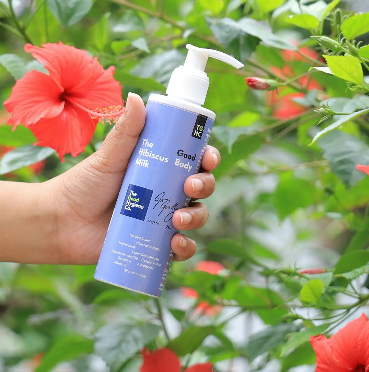 Hand holding a bottle of hibiscus body lotion.