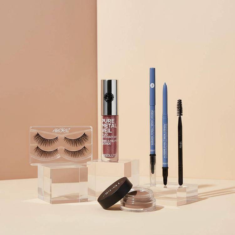 Eye makeup collection featuring false eyelashes, eyeshadows, eyeliners, and brow products on minimalist nude background